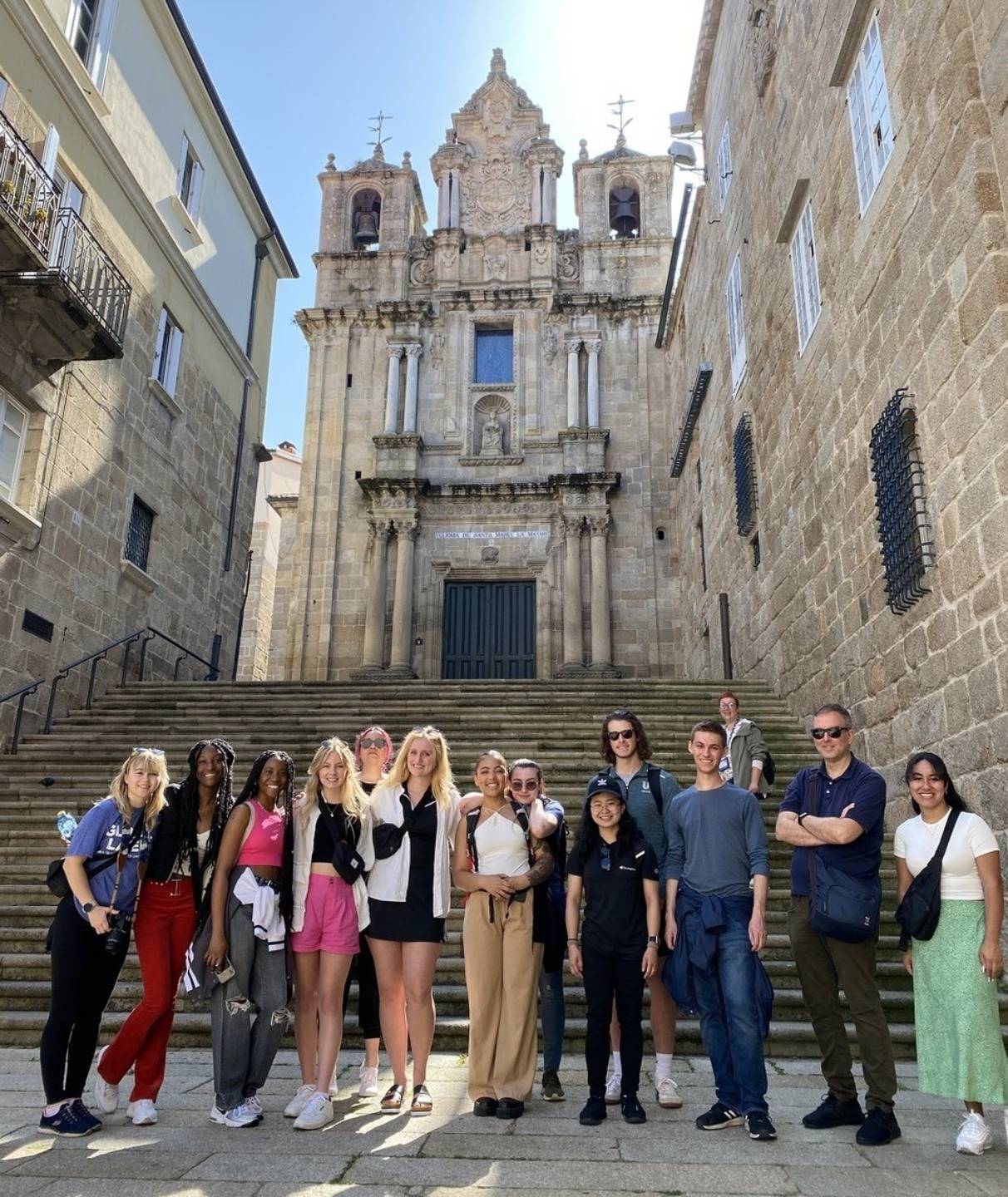 a group of students posing in front of the stone steps of a church in Spain